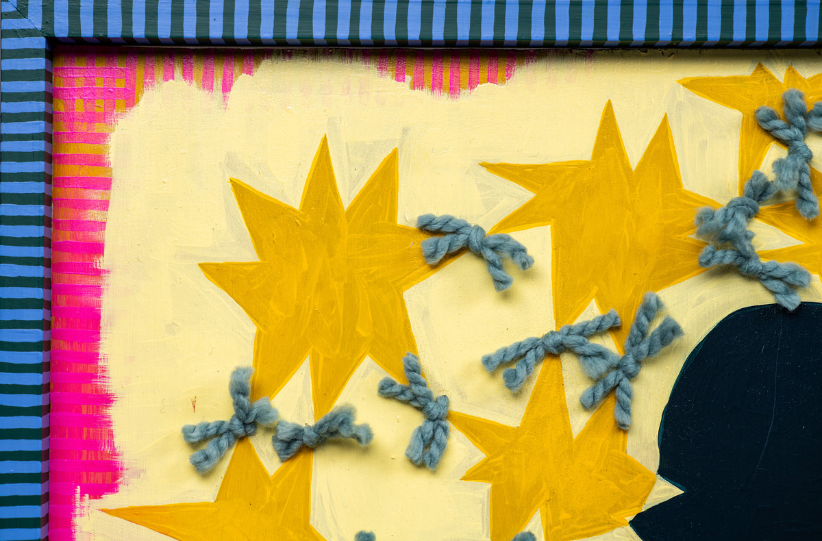 Detail of Crazy Girl by Sydney Noland: golden yellow stars tied with gray yarn on a pale yellow background, with a blue striped frame edge