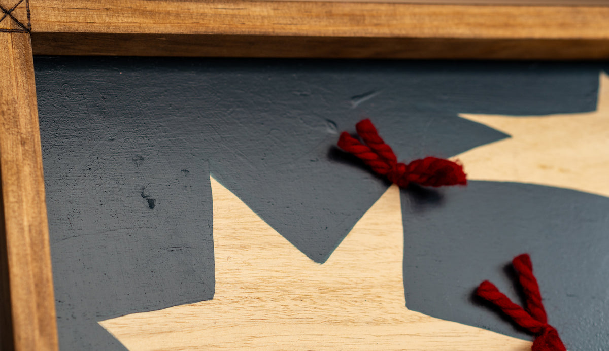Detail of Quilt by Sydney Noland: close-up of the wood frame edge, a red yarn knot, and a wood star on deep blue